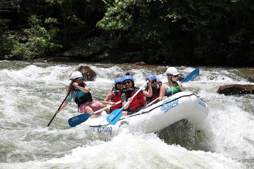 A group of people rafting on a river surrounded by dense greenery. 2