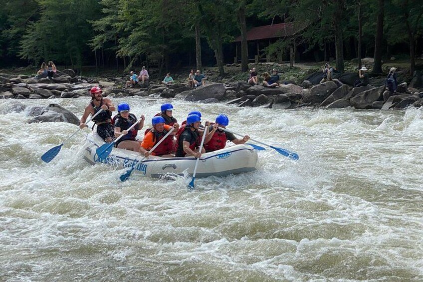 Un grupo de personas en una balsa blanca navegando un río con rápidos. 5