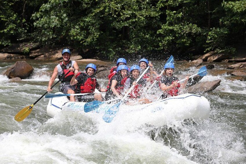 Een groep mensen in een witte raft die een rivier met stromingen afvaart. 2