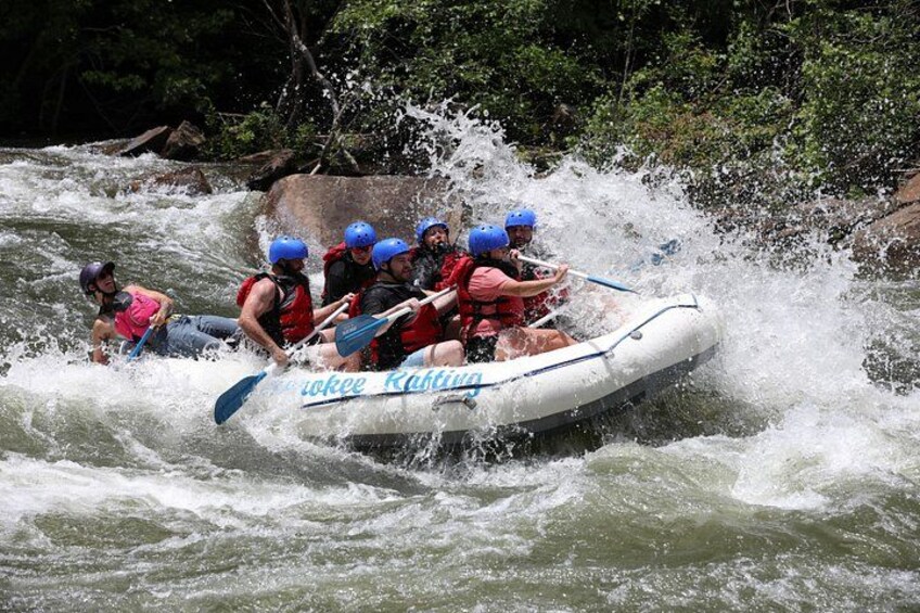 Un grupo de personas en un bote inflable blanco navega por un río con rápidos. 3