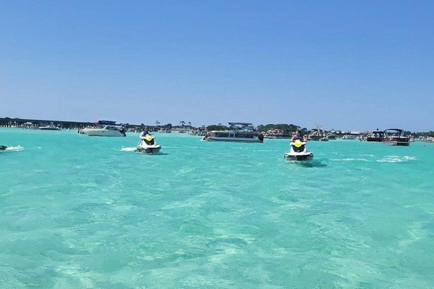 A clear turquoise sea with several boats and a pier in the background. 2