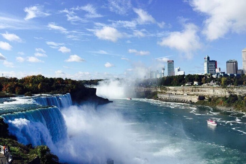 A waterfall cascading into a river with a city skyline in the background. 5