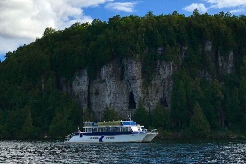 Un barco llamado SCENIC TOURS navegando en un cuerpo de agua, con un acantilado boscoso al fondo. 5