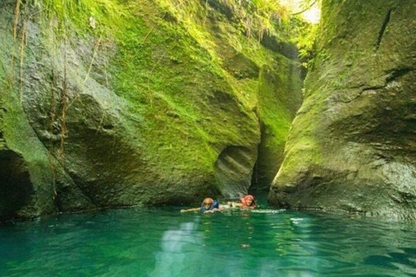 A cave with green moss and a person in a kayak. 4