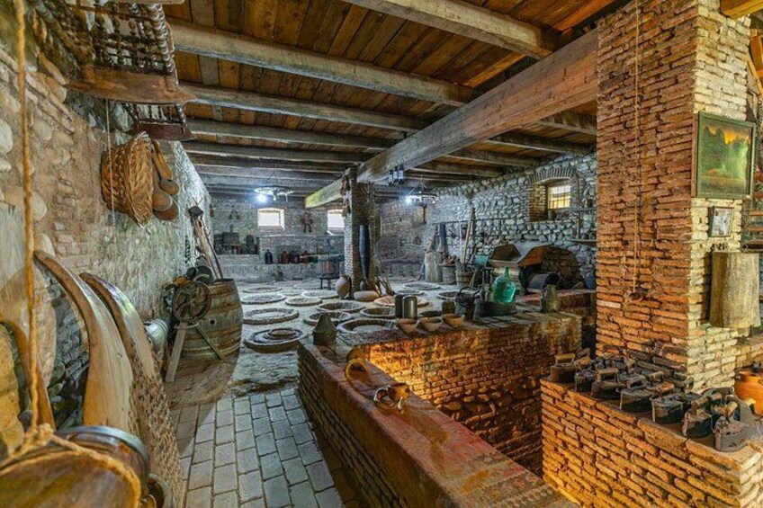 A rustic interior with brick walls, wooden beams, and various tools and pottery. 5