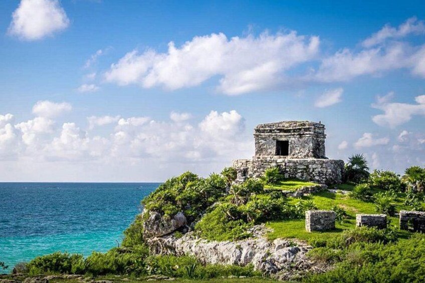 A stone structure on a grassy cliff by the sea. 3