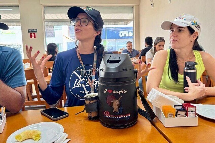 A person with a black backpack and a water bottle at a table with a coffee maker. 4