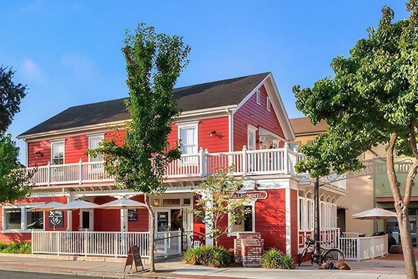 Un edificio rojo con balcón, asientos exteriores y un letrero que dice 'All Day Cafe'. 2