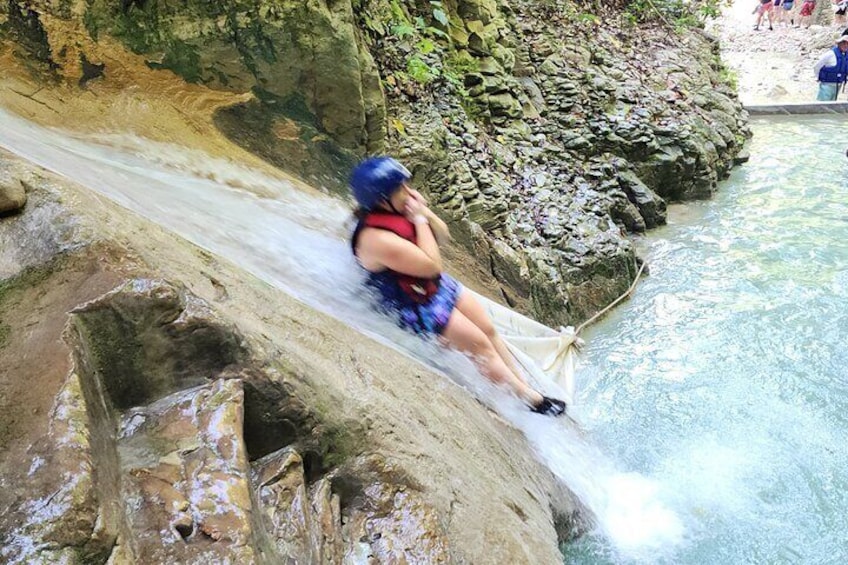 A person sliding down a rocky slope into a body of water. 4