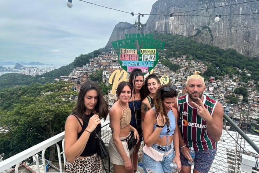 Un groupe de personnes se trouve sur un pont, avec une vue sur la ville et une montagne en arrière-plan. 5