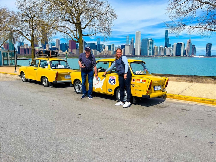 Two yellow vintage cars parked by a waterfront with a city skyline in the background. 5