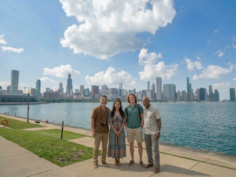 A group of people standing by a waterfront with a city skyline in the background. 1