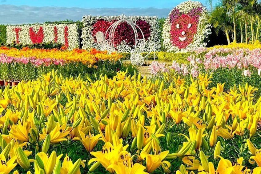 A garden with yellow lilies, a heart-shaped flower arrangement, and a carousel. 1