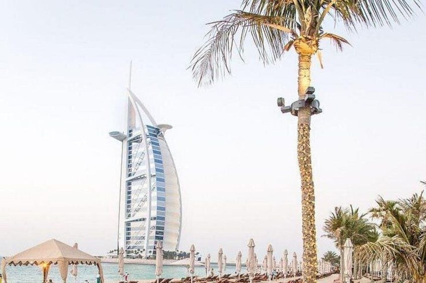 En palme, en strand med parasoller, og Burj Al Arab hotellet. 5