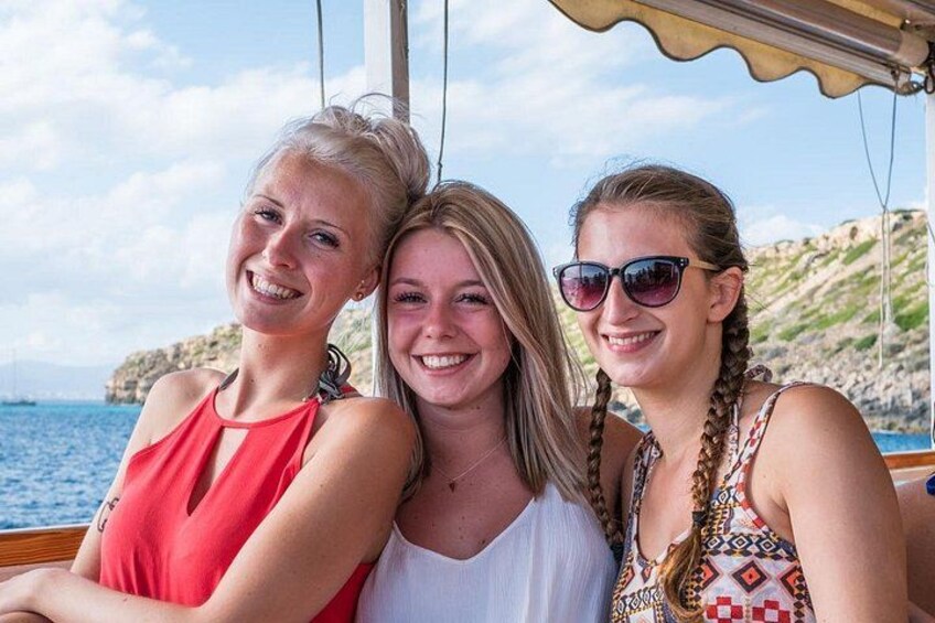 Drei Personen in einem Boot vor einer felsigen Küste mit dem Meer im Hintergrund. 4