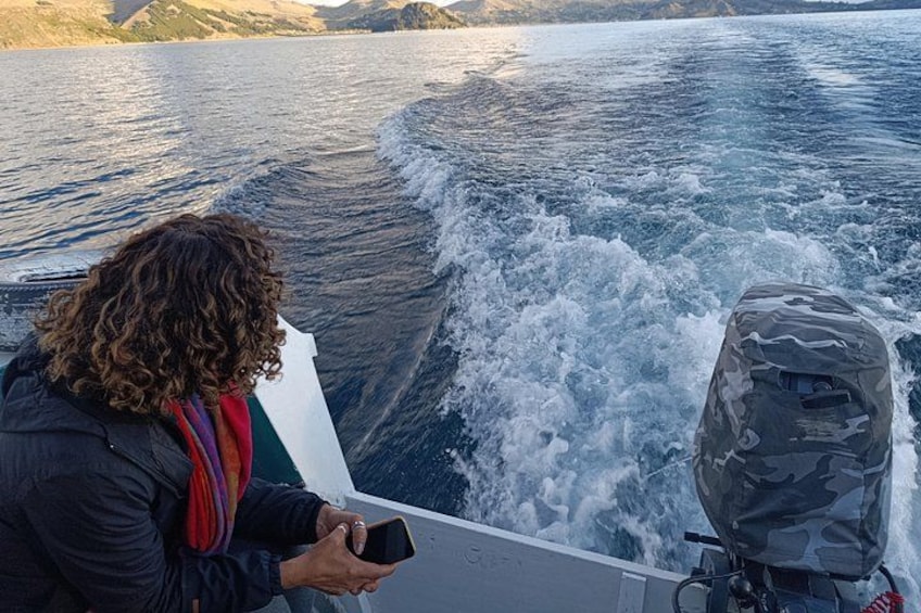 Iemand in een boot met een motor, die naar een smartphone kijkt. 2