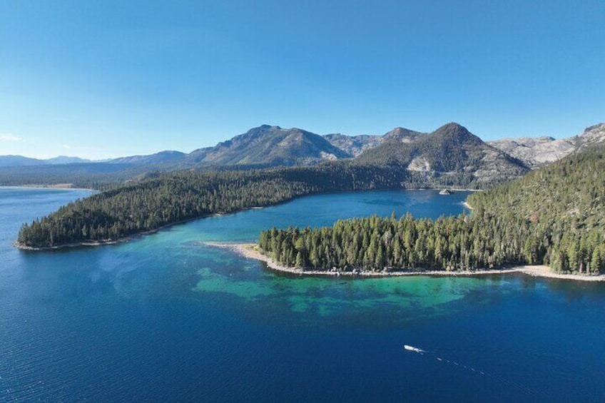 Paisaje costero con una isla boscosa rodeada de aguas azules cristalinas y montañas a lo lejos. 3