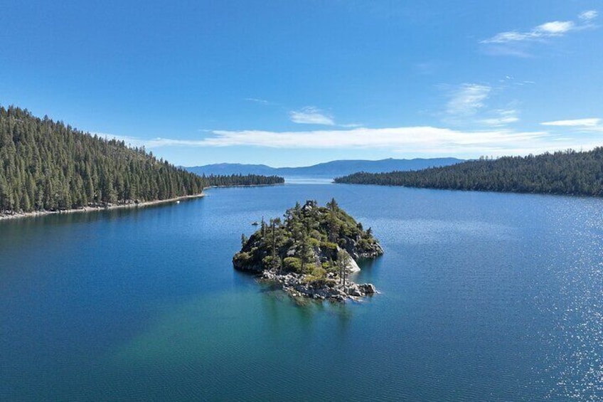 Una extensa masa de agua con una pequeña isla en el centro, rodeada de densos bosques. 4
