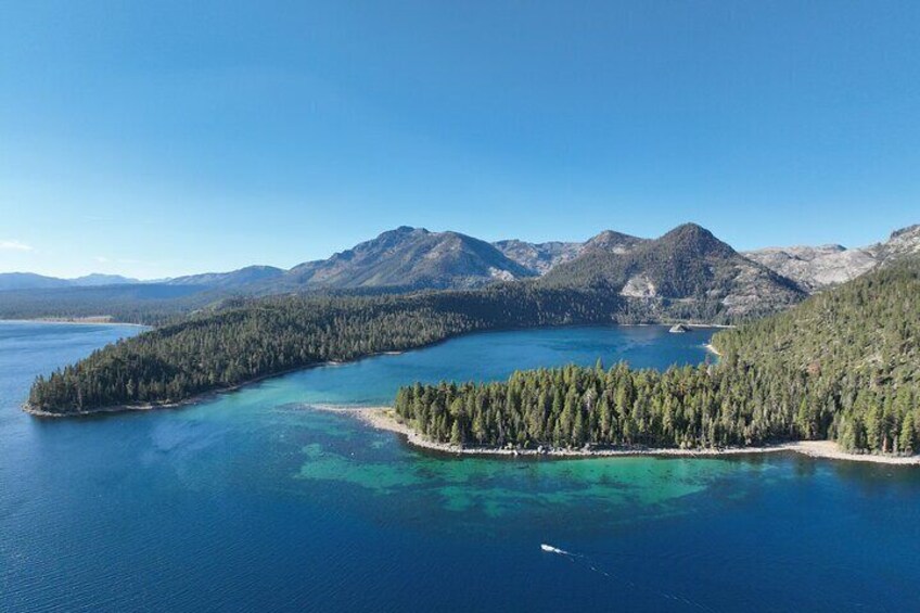 A coastal landscape with a forested island and mountains in the background. 5