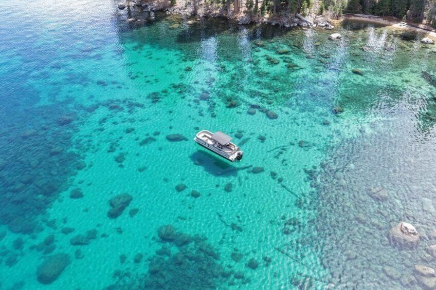 A boat on clear turquoise water with visible rocks and a rocky shoreline. 3
