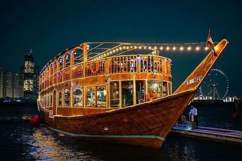 Un bote de madera con cubierta superior protegida, atracado en un muelle con un horizonte urbano y una noria al fondo. 1