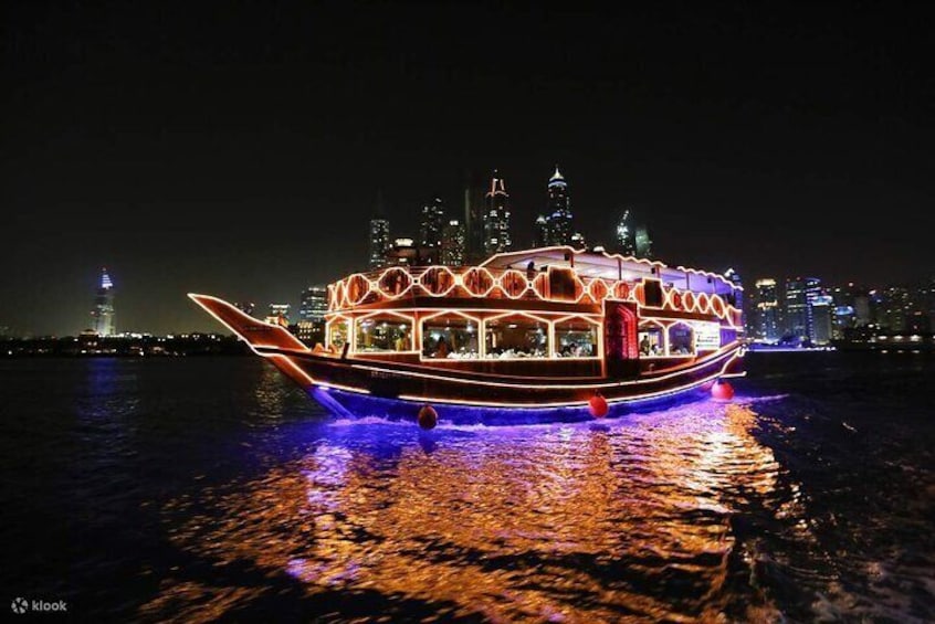Un barco bien iluminado con diseños circulares en la cubierta, flotando sobre el agua con un horizonte urbano al fondo. 2