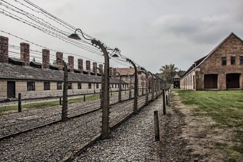 Un bâtiment historique à la façade en briques, doté d’une longue zoneClosement délimitée par une clôture en fil de fer barbelé. 2