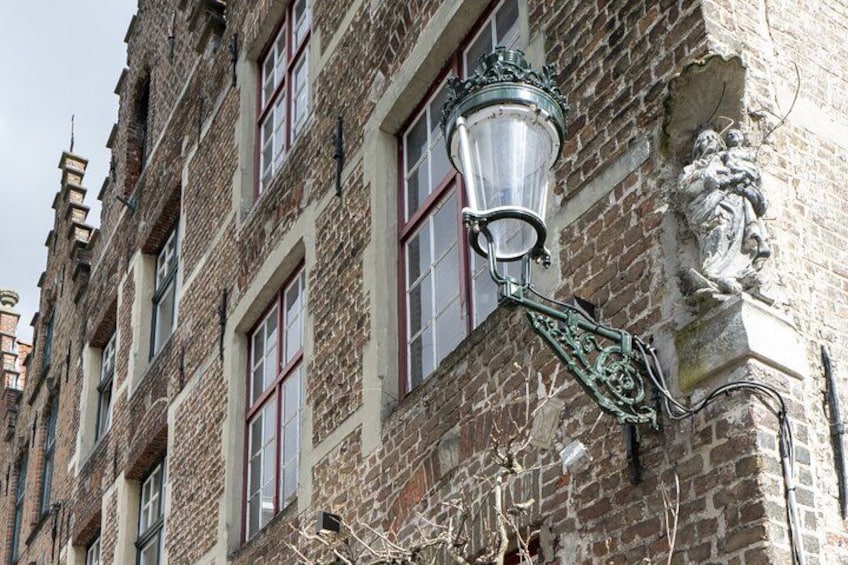 Un edificio histórico con fachada de ladrillo, marcos de ventanas ornamentados y un farol decorativo. 2