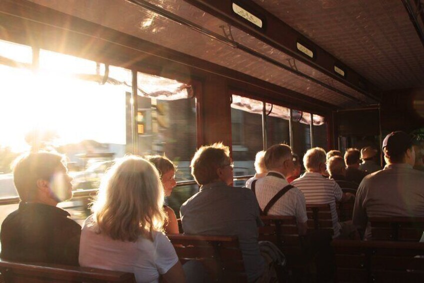 People seated inside a vehicle, possibly a bus or train, with sunlight streaming through the windows. 3