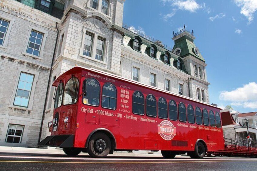 A red trolley with advertisements for City Hall and 1000 Islands. 1