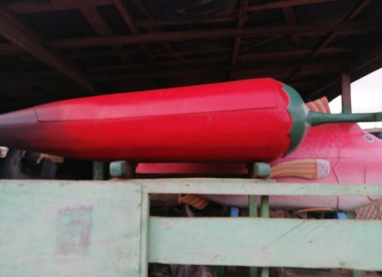 A large red object, possibly a piece of equipment, under a shelter with a green frame. 4