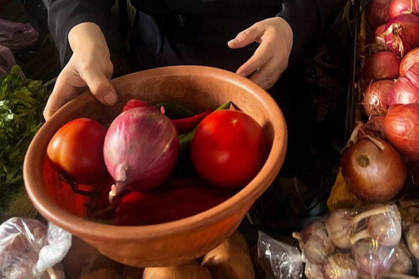 Iemand houdt een kom vast met tomaten en uien. 2