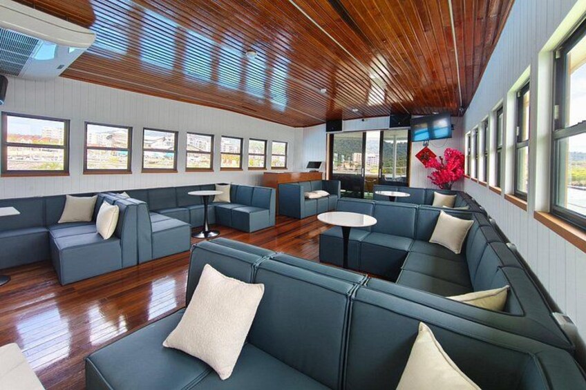 A modern interior with wooden ceilings, blue seating, and large windows. 4