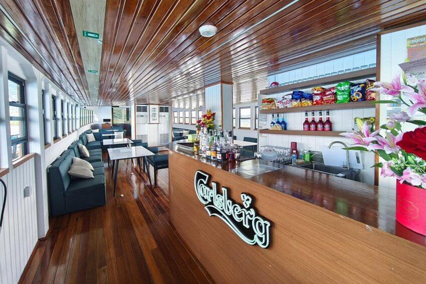 A wooden bar area with a sign reading 'Cadberg,' seating arrangements, and a snack shelf. 3