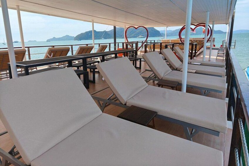 A deck with sun loungers and heart-shaped decorations, overlooking a body of water and distant land. 5