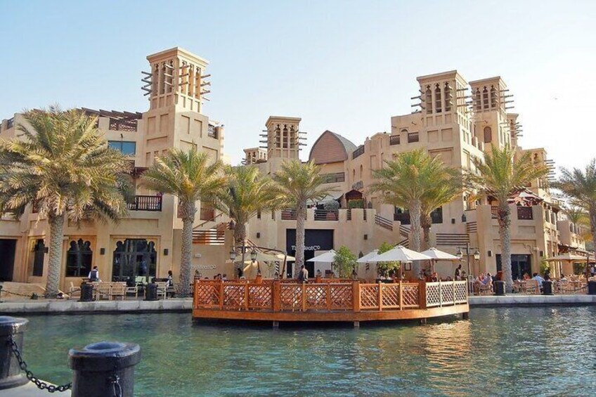 A waterfront area with palm trees, a wooden bridge, and buildings with traditional architecture. 3