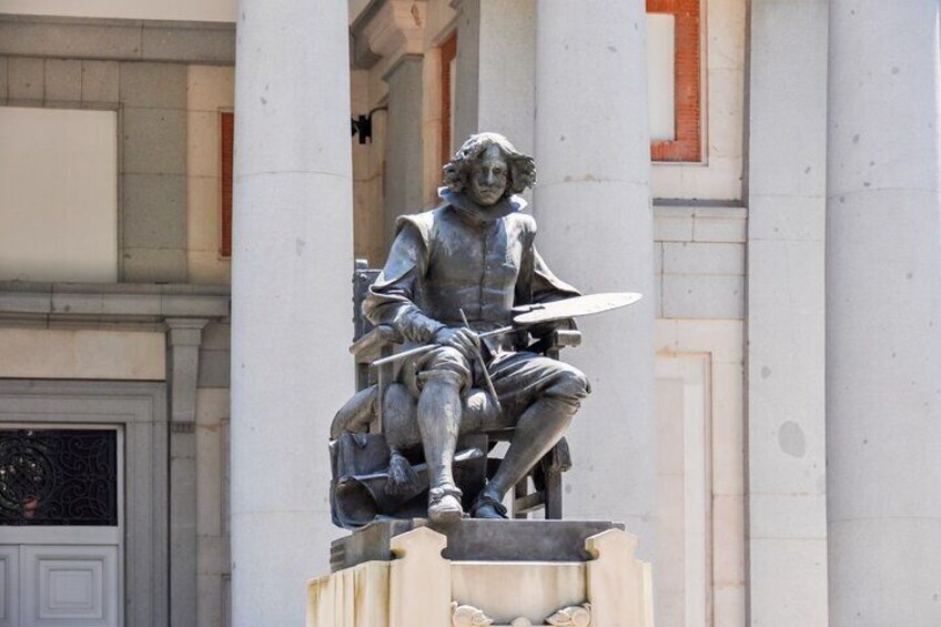 A statue of a seated figure holding a sword, mounted on a pedestal, with columns in the background. 4