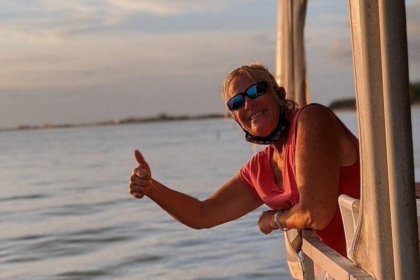 A person leaning on a wooden railing by a body of water during sunset. 2