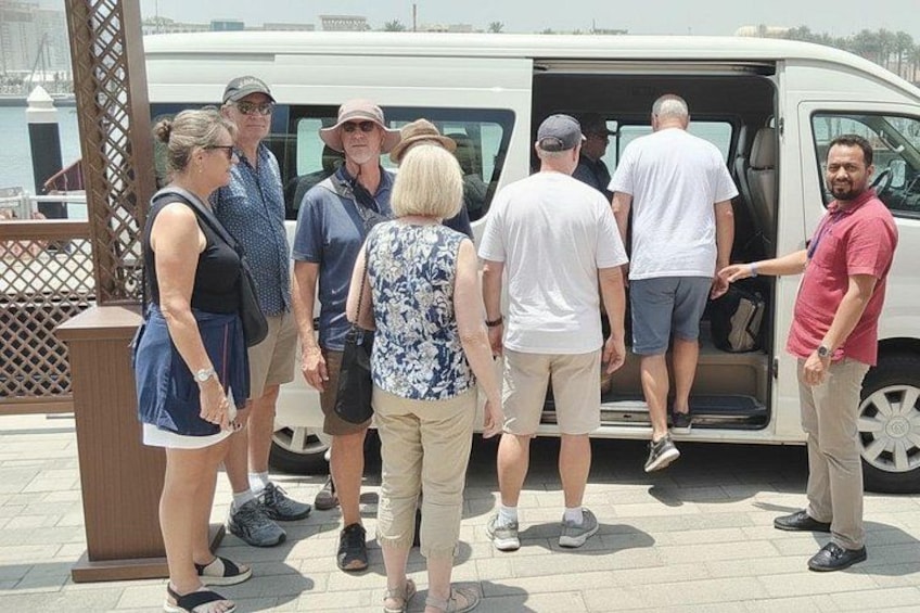 A group of people standing in front of a white van with its door open. 4