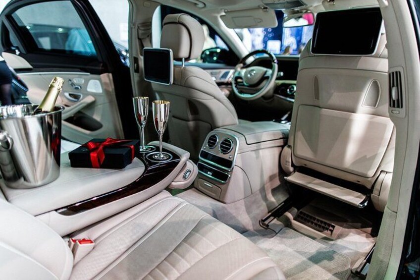 A luxurious car interior with a champagne bucket, two glasses, and a gift box. 2