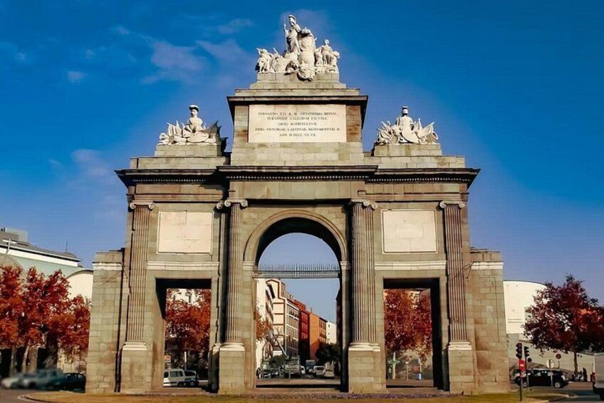 A large stone archway with statues on top and a plaque in the center. 3