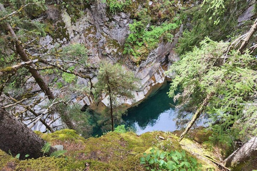 A natural landscape with a water body surrounded by rocky terrain and dense vegetation. 2