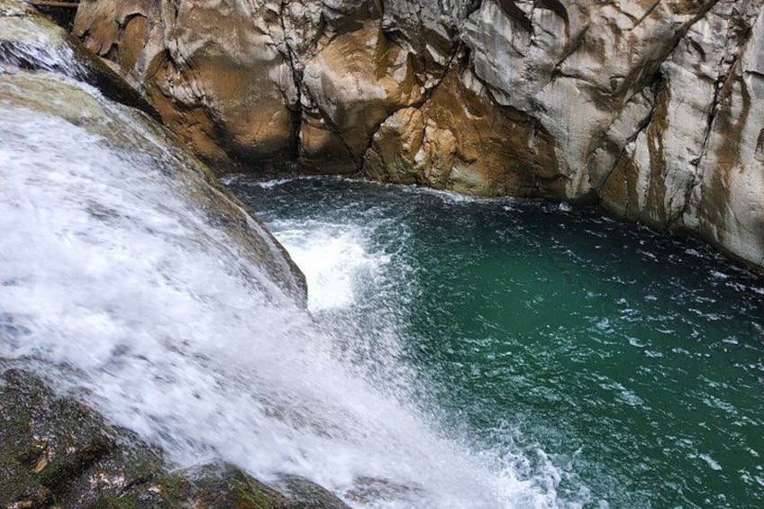A waterfall cascading into a turquoise pool surrounded by rocky cliffs. 3