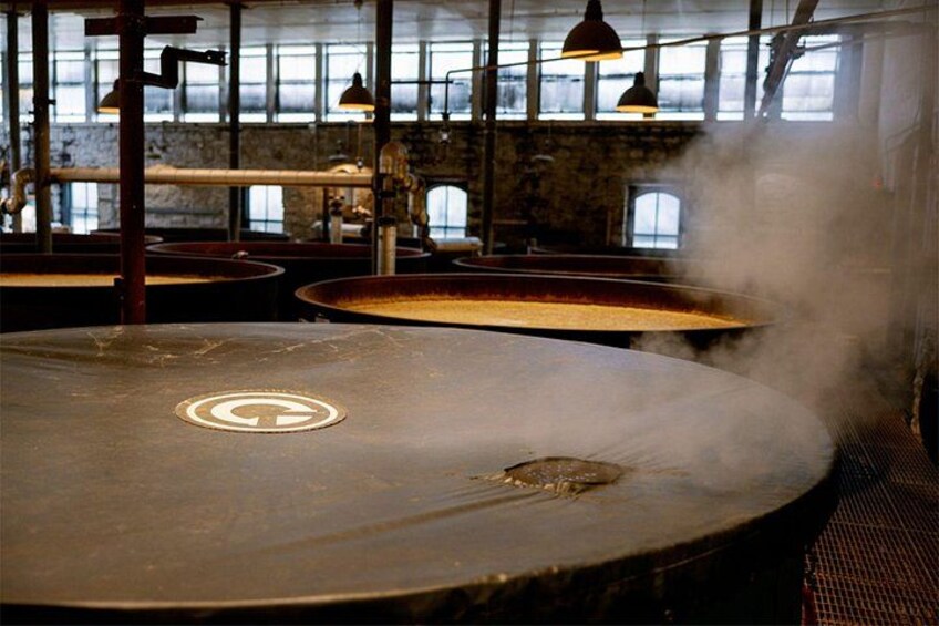 A steamy kitchen with large pots, industrial lighting, and a rustic brick wall. 3