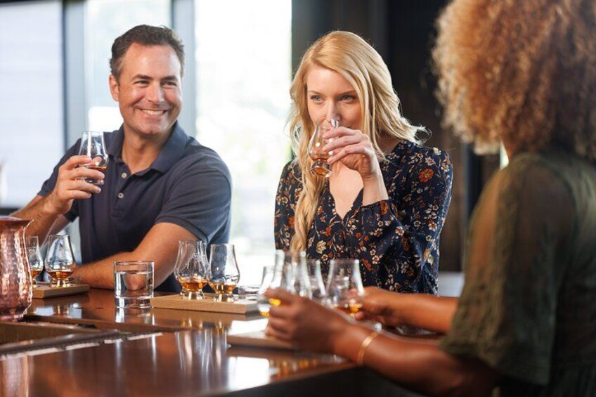 A group of people sitting at a bar with glasses of whiskey. 2