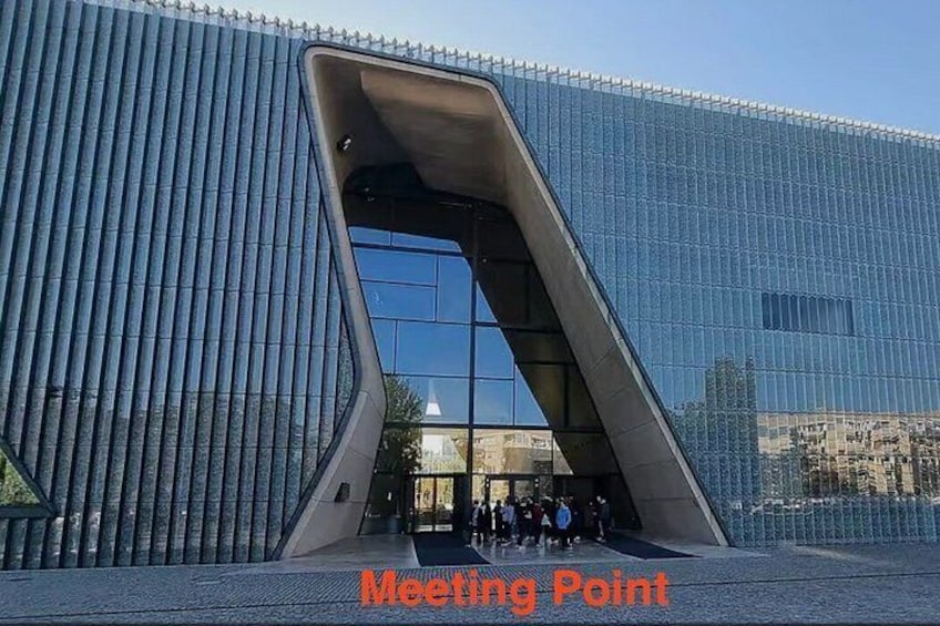 A modern building with a unique angular entrance and reflective glass facade. 2