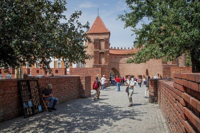A historic brick wall with a tower, a cobblestone path, and people walking. 5