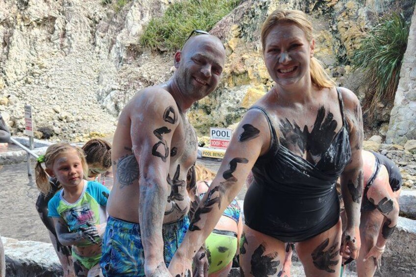 Un grupo de personas con pintura negra en el cuerpo, de pie cerca de una piscina con un fondo rocoso. 5