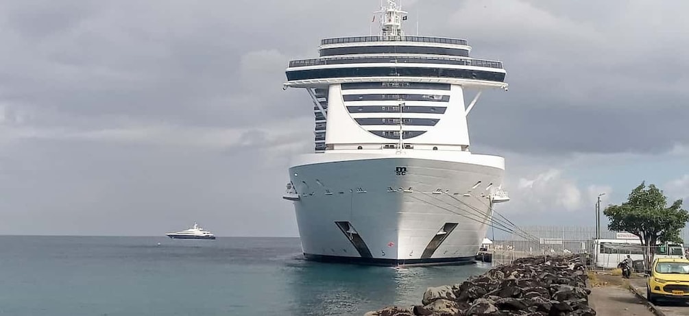 Un gran crucero amarrado en un puerto, con un barco más pequeño al fondo. 4