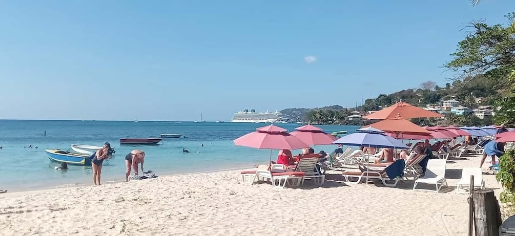 Una playa con gente tomando el sol, barcos y sombrillas. 5